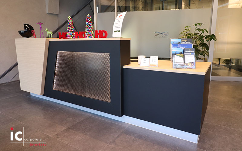 Custom made reception desk with metal mesh feature panel with LED light behind.